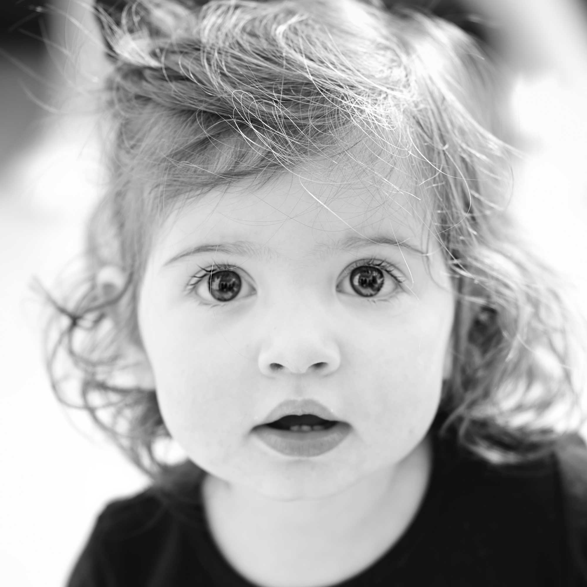 timeless-black-and-white-child-portrait-curious-gaze_beautiful Black and white portrait of a young girl with a deep, captivating gaze that embodies presence, confidence, and timeless beauty.